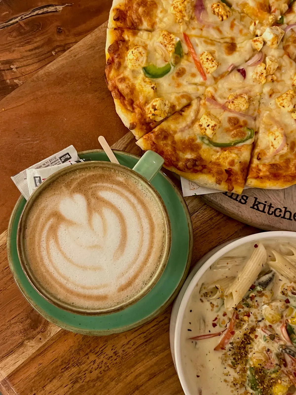 Representative pizza pasta and latte on a café table
